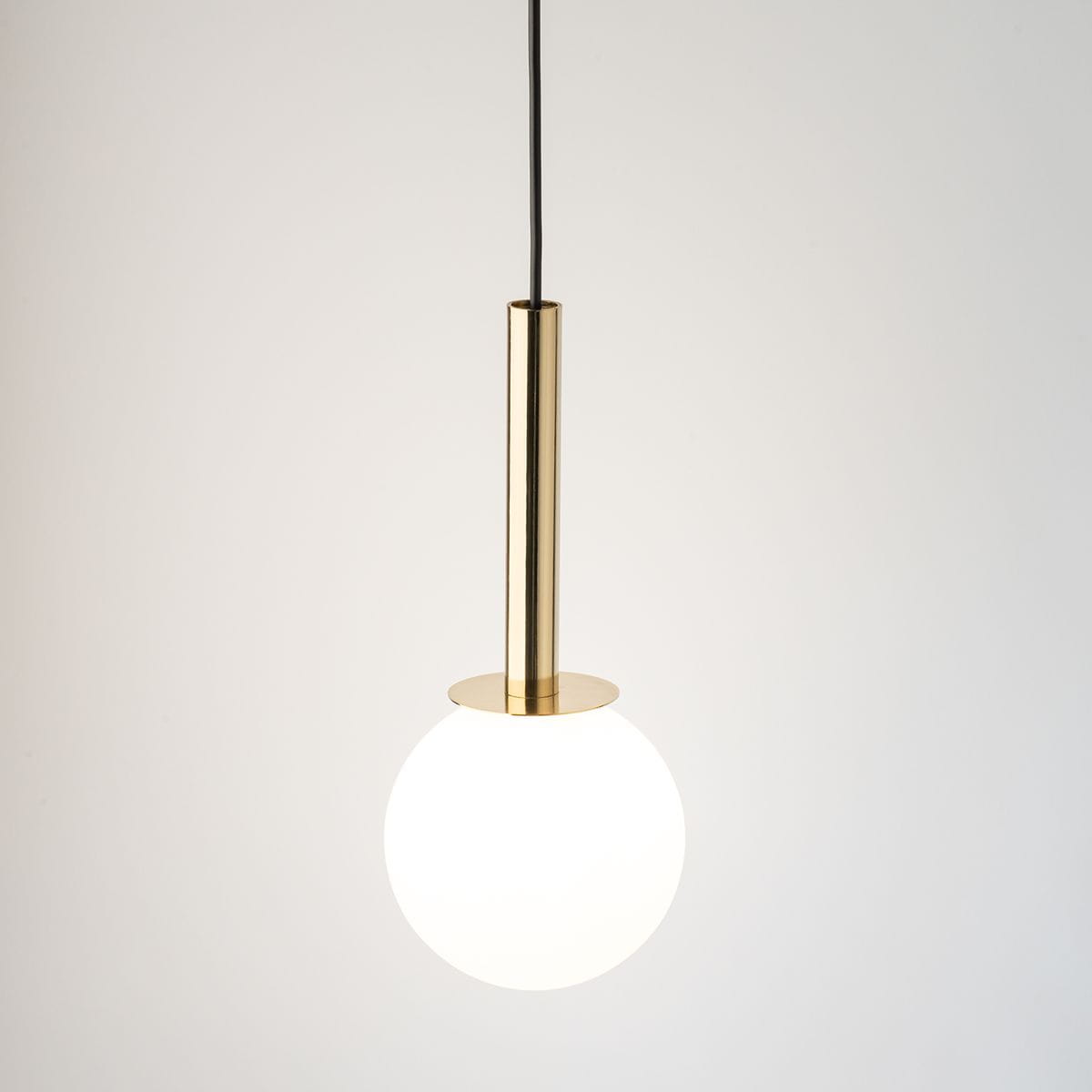 Lampa wisząca Daisy 1xG9 w kolorze złotym z białym, okrągłym kloszem. Stojąca na cienkim, złotym słupku z podstawką. Zawieszona na czarnym przewodzie, na jasnym tle. Prosty, nowoczesny design idealny do różnych wnętrz.