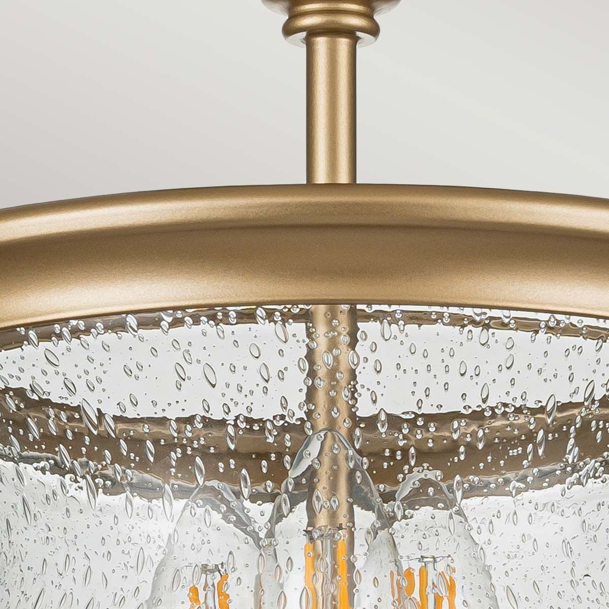Lampa sufitowa Pickering w kolorze mosiądzu z trzema miejscami na żarówki E14. Szklany klosz z efektem kropli wody, wiszący na metalowej konstrukcji. Widok z góry, ukazujący detale i teksturę klosza.