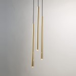 Lampa wisząca Sopel Lux w kolorze czarnym i złotym, składająca się z trzech cienkich, cylindrycznych elementów. Zawieszona na czarnych linkach, emitująca światło z dolnej części, na jasnym tle.
