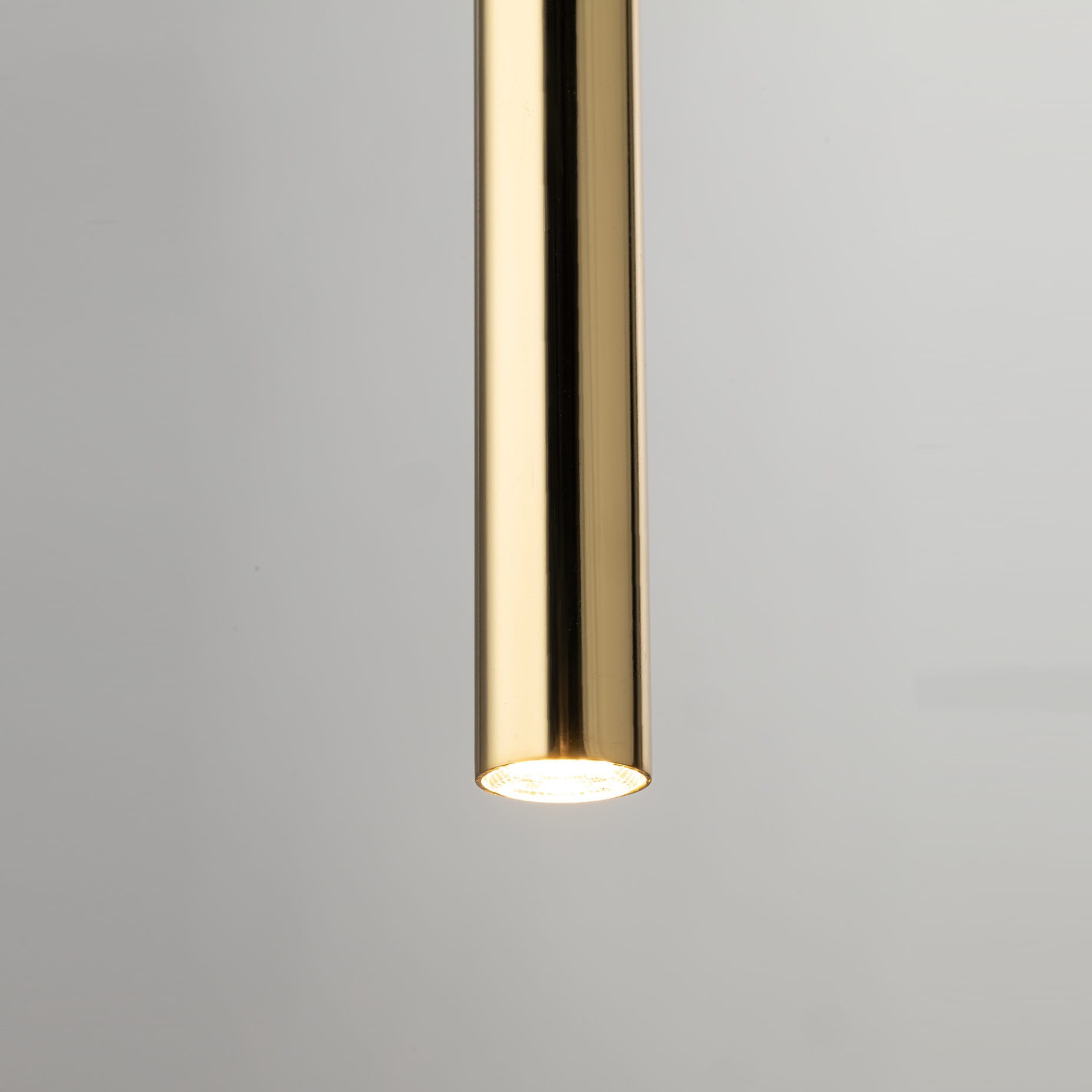 Lampa wisząca Sopel Lux w kolorze czarnym i złotym, z pięcioma źródłami światła G9. Zbliżenie na złoty, cylindryczny klosz z widoczną żarówką, zawieszony w pionie. Tło w odcieniu szarym, co podkreśla elegancki wygląd lampy.