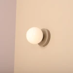 Kinkiet Ball II S w kolorze beżowym z kulistym, matowym kloszem. Zamontowany na ścianie, z metalową podstawą. Oświetlenie przeznaczone do jednej żarówki E14. Prosty, nowoczesny design, idealny do różnych wnętrz.
