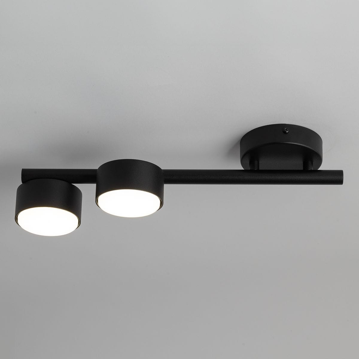 Lampa sufitowa Punto z dwoma okrągłymi źródłami światła GX53 w kolorze czarnym. Metalowa konstrukcja z prostą, poziomą listwą, zamontowana na okrągłej podstawie. Kąt ujęcia z góry, ukazujący detale lampy.