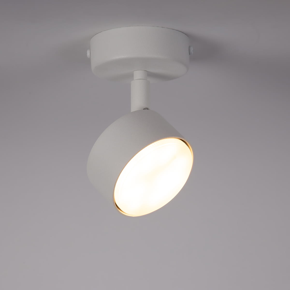 Lampa sufitowa Nemo H15 w kolorze białym, z regulowanym kloszem w formie okrągłej. Zamontowana na okrągłej podstawie z metalu, z oprawą na żarówkę GX53. Klosz emitujący ciepłe światło, widoczny w zbliżeniu.