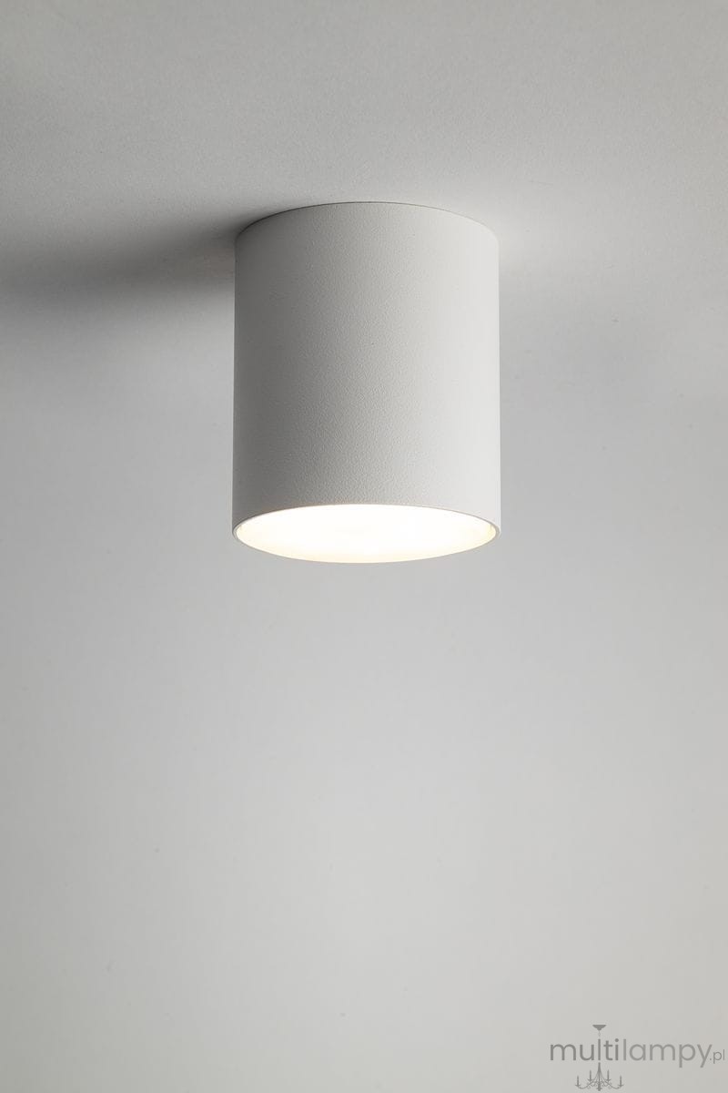 Lampa sufitowa Tubo H9,5 w kolorze białym, wykonana z matowego materiału. Okrągły kształt, montowana na suficie. Widoczna oprawa na żarówkę GX53, emitująca światło z dolnej części lampy. Tło jasne, jednolite.