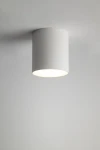 Lampa sufitowa Tubo H9,5 w kolorze białym, wykonana z matowego materiału. Okrągły kształt, montowana na suficie. Widoczna oprawa na żarówkę GX53, emitująca światło z dolnej części lampy. Tło jasne, jednolite.