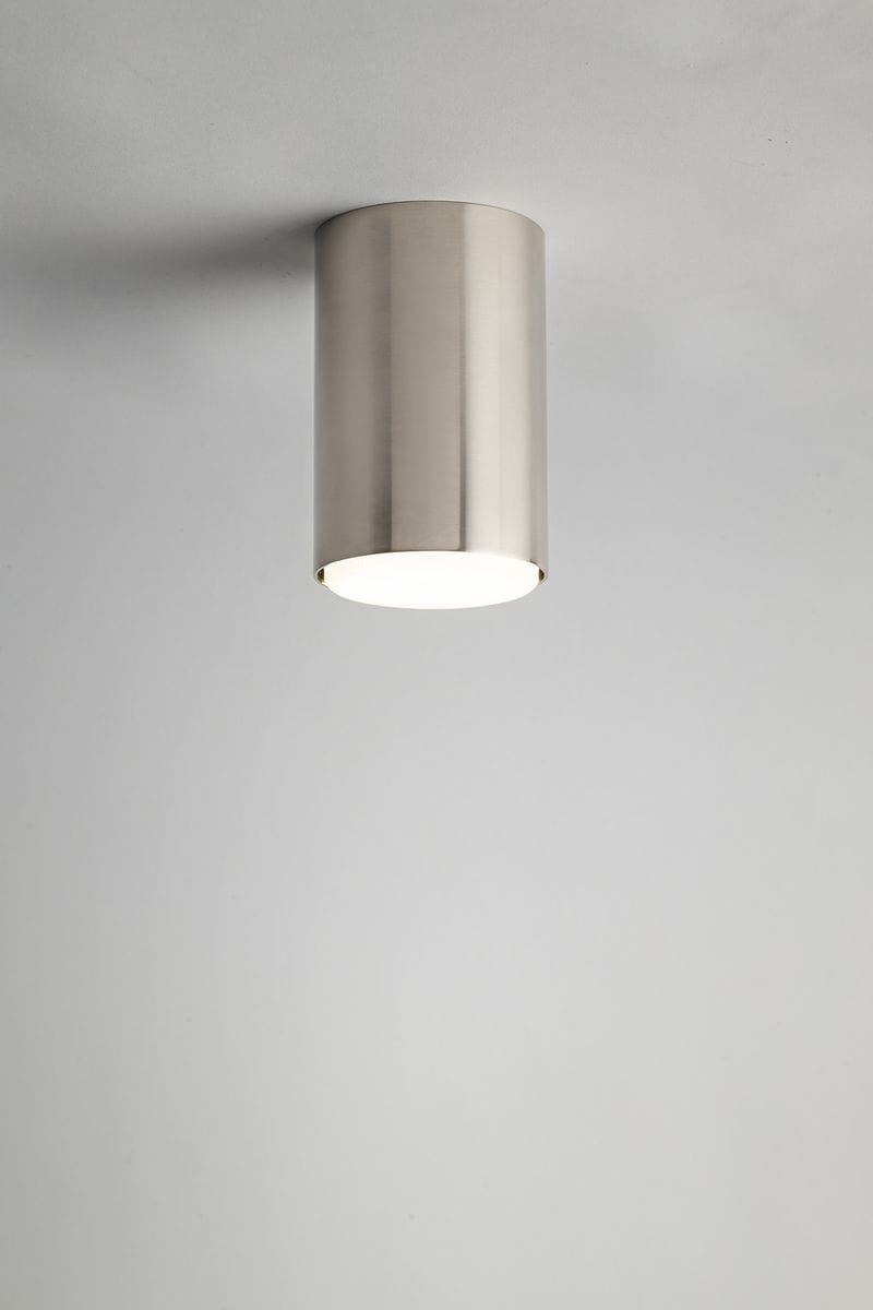 Lampa sufitowa Tubo H12,5 w kolorze srebrnym, wykonana z matowego metalu, o cylindrycznym kształcie. Ujęcie frontalne, zamontowana na suficie, z widocznym źródłem światła GX53. Tło jasnoszare, minimalistyczne.