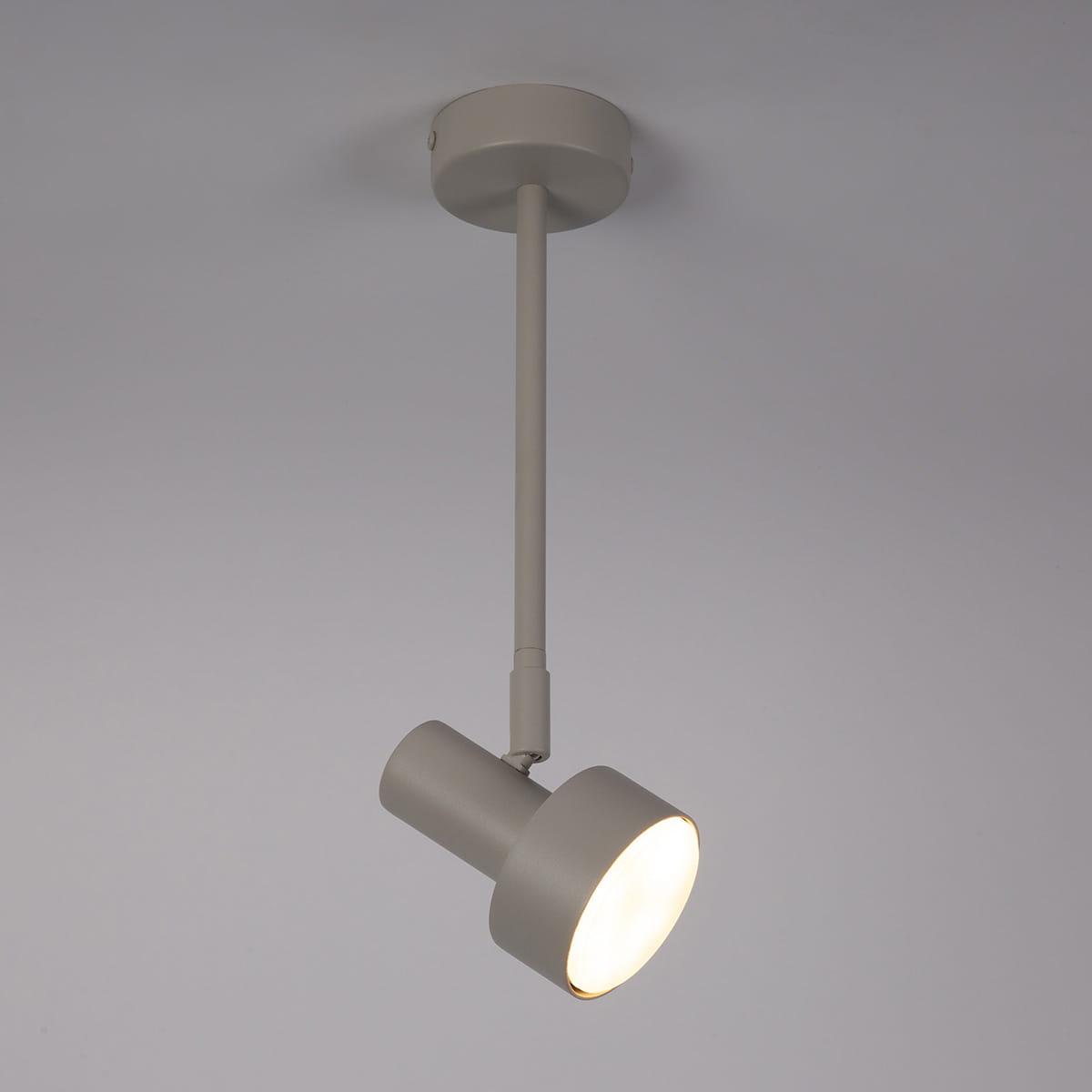 Lampa wisząca Mona H36 w kolorze szarym i beżowym, z jednym punktem świetlnym na mocowanie GX53. Ujęcie z boku, ukazujące okrągłą głowicę emitującą światło, zawieszona na cienkim wysięgniku z sufitu. Tło jednolite, jasne.