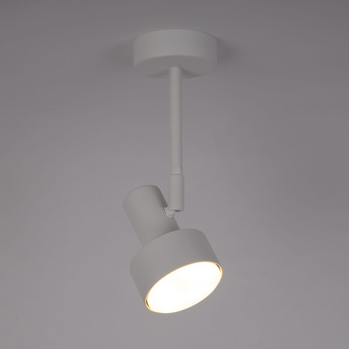Lampa wisząca Mona H25 w kolorze białym, z metalowym kloszem w kształcie cylindra, zawieszona na cienkim stelażu. Kąt ujęcia zbliżenie, ukazujące oprawę GX53 z jasnym źródłem światła, montowana do sufitu.