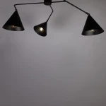 Czarna lampa sufitowa Galaxy z trzema kloszami w kształcie stożków, zamontowana pod kątem. Klosze są matowe, z widocznymi żarówkami E27. Tło jest jasnoszare, co podkreśla elegancki design lampy.