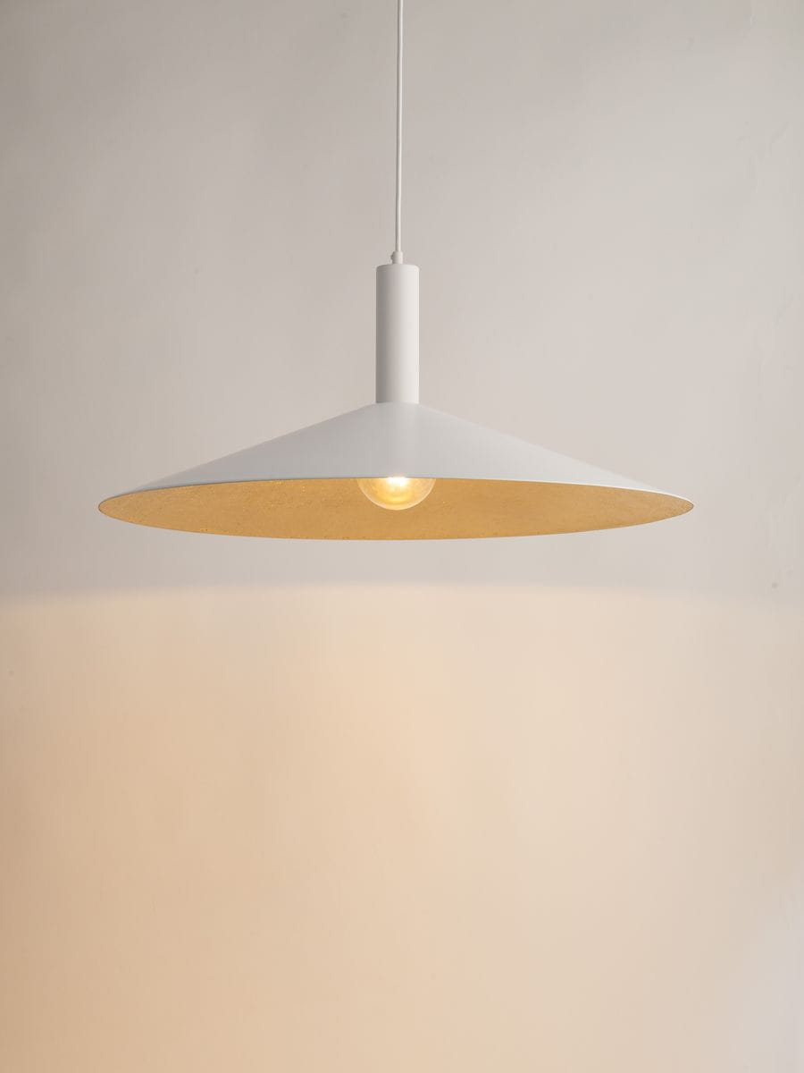 Lampa wisząca Capri D70 z kloszem w kształcie stożka, wykonana z białego metalu z wewnętrzną złotą powierzchnią. Zawieszona na cienkim przewodzie, widoczna żarówka E27. Prosta, nowoczesna forma, na jednolitym tle.