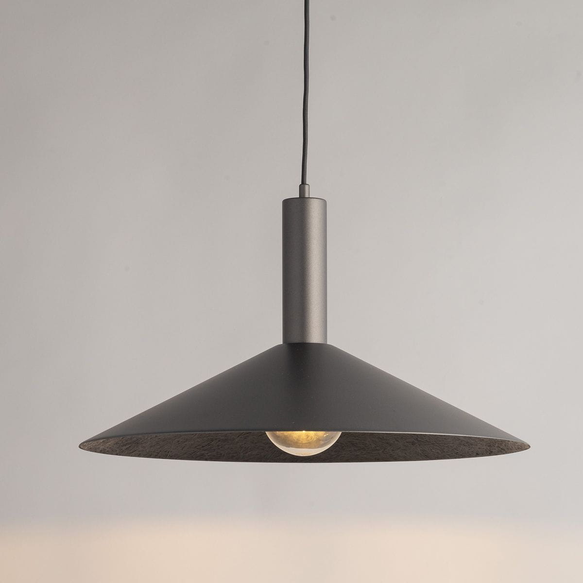 Srebrna lampa wisząca Capri D50 z kloszem w kształcie stożka, zawieszona na cienkim przewodzie. Widoczna żarówka E27 w środku klosza, wykonana z metalu o matowej fakturze. Prosty, nowoczesny design, idealna do wnętrz.