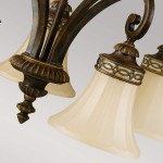 Lampa wisząca Drawing Room, postarzany brąz, z pięcioma kloszami w kształcie dzwonu z matowego szkła. Uchwyt ozdobiony detalami w złotym kolorze, styl vintage. Klosze zamocowane na eleganckich ramionach, z widocznymi dekoracyjnymi elementami.