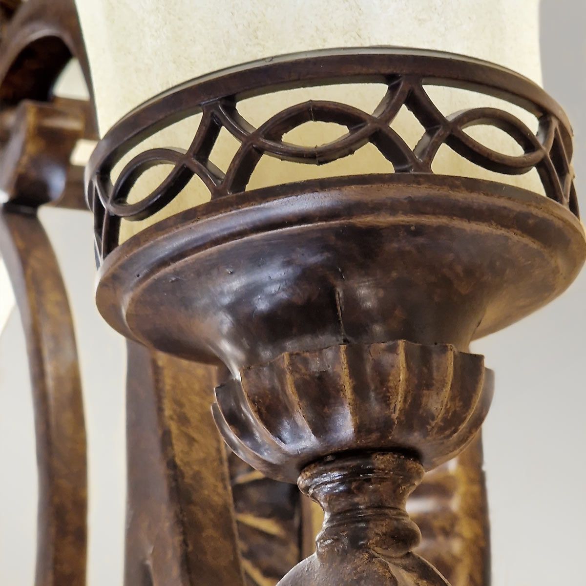 Kinkiet Drawing Room w postarzanym brązie, z ozdobnym metalowym abażurem i detalami w kształcie fal. Produkt widoczny z bliska, podkreślający teksturę i detale rzeźbionej podstawy. Idealny do wnętrz w stylu vintage.