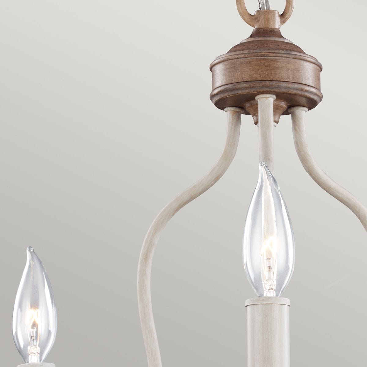 Lampa wisząca Hartsville w kolorze kredowej bieli, z trzema miejscami na żarówki E14. Posiada drewniany uchwyt i delikatne, zakrzywione ramiona, które podkreślają elegancki design. Ujęcie z góry, pokazujące detale konstrukcji.