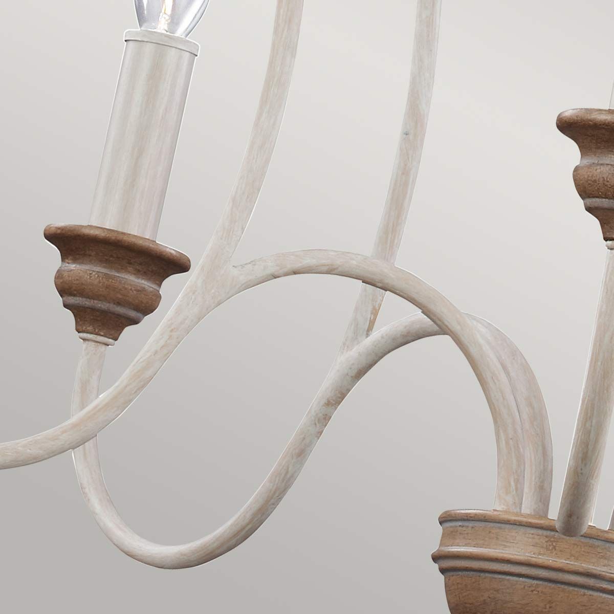 Lampa wisząca Hartsville w kredowej bieli z pięcioma miejscami na żarówki E14. Elementy metalowe w jasnym wykończeniu, z drewnianymi akcentami. Ujęcie z boku, pokazujące fantazyjnie wygięte ramiona i detale mocowania.