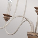 Lampa wisząca Hartsville w kredowej bieli z pięcioma miejscami na żarówki E14. Elementy metalowe w jasnym wykończeniu, z drewnianymi akcentami. Ujęcie z boku, pokazujące fantazyjnie wygięte ramiona i detale mocowania.