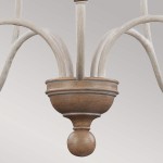 Lampa wisząca Hartsville w kredowej bieli z pięcioma ramionami na żarówki E14. U podstawy znajduje się dekoracyjny, okrągły element w kolorze naturalnego drewna, z subtelnymi zdobieniami. Ramiona mają delikatnie teksturowaną powierzchnię.