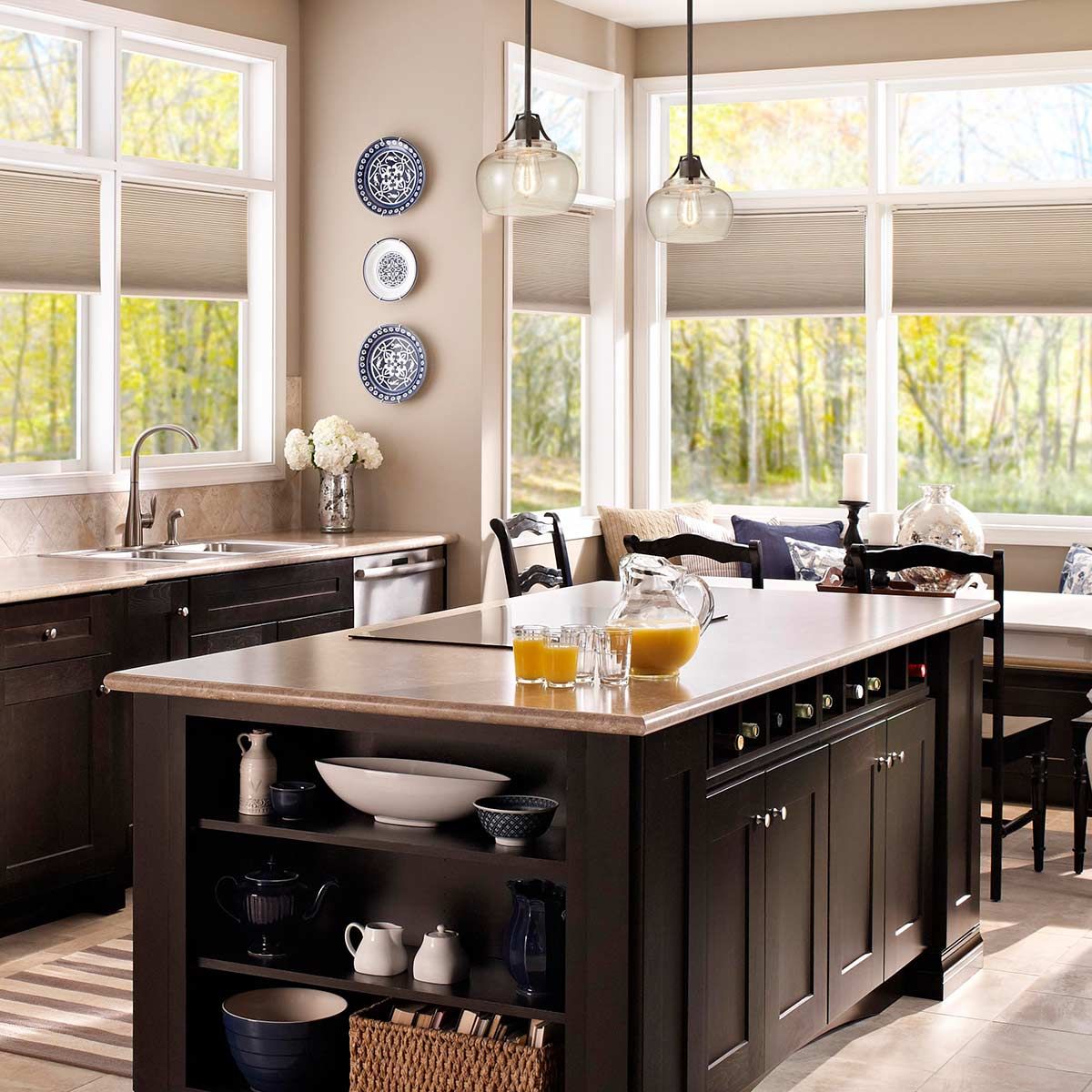 Lampa wisząca Urban Renewal S z rustykalnym żelazem, umieszczona w nowoczesnej kuchni. Okrągłe klosze w przezroczystym szkle zawieszone nad wyspą kuchenną. W tle widoczne okna z widokiem na zewnątrz oraz dekoracyjne talerze na ścianie.