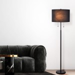 Lampa podłogowa Fogo 2xE27 w kolorze czarnym, z okrągłą podstawą, prostym metalowym stelażem oraz cylindrycznym kloszem z tkaniny. Ujęcie z boku, obok ciemnoszarej sofy, na jasnym tle. Włączniki w postaci metalowych kul.