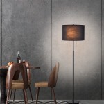 Czarna lampa podłogowa Fogo LP-0304/2F BK z dwoma gniazdami E27. Okrągła, materiałowa abażur w ciemnym kolorze, stojak w minimalistycznym stylu. Umieszczona obok stołu w jadalni, na tle szarej ściany.