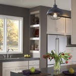 Lampa wisząca Urban Renewal z antycznego kutej żelaza w kolorze czarnym, zawieszona nad blatem kuchennym. Posiada metalowy klosz w kształcie kopuły z siatką, z widoczną żarówką E27. Tło w jasnych odcieniach, z elementami dekoracyjnymi na półkach.