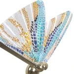 Lampa wisząca Mariposa z jednym źródłem LED 8W, w złotej oprawie. Klosz w kształcie motyla z kolorowym, szklanym wzorem w odcieniach niebieskiego, pomarańczowego i złotego, umieszczony pod kątem, eksponując detale.