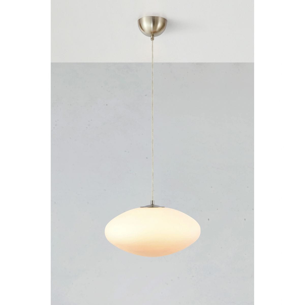 Locus lampa wisząca 1xE14 w kolorze białym, o owalnym kształcie z matowego szkła, zawieszona na cienkim przewodzie. Metalowy stelaż w kolorze stalowym. Lampa wisząca umieszczona na jasnym tle, co podkreśla jej elegancki design.