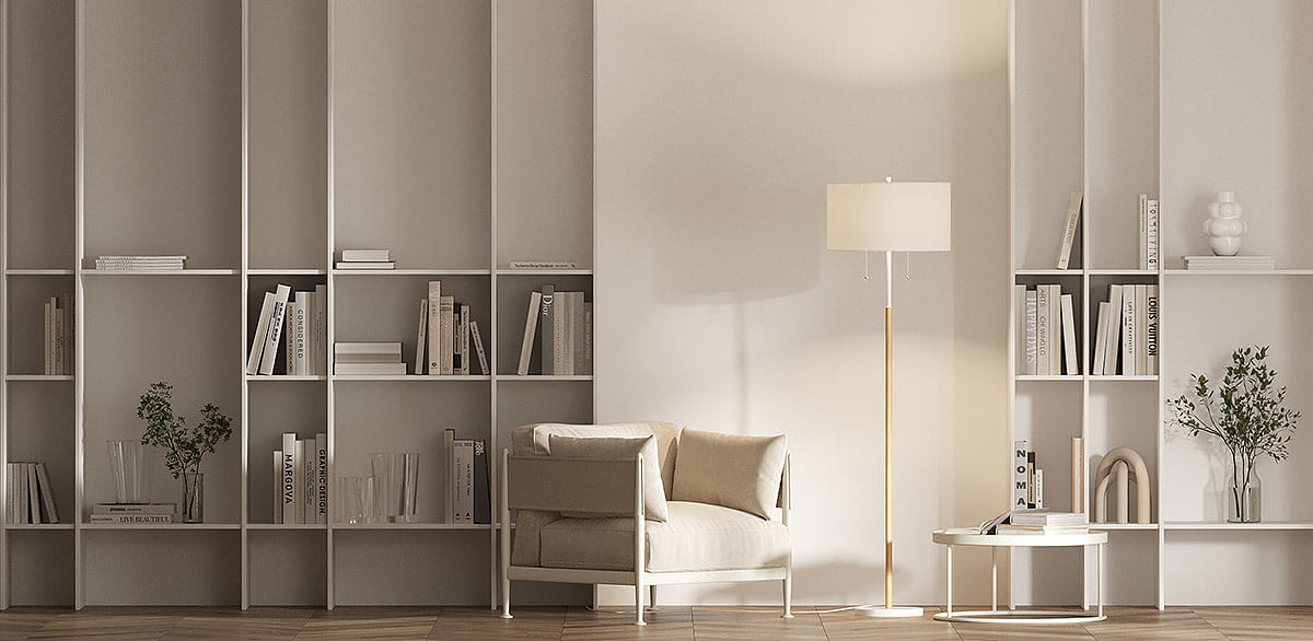 Lampa podłogowa Fogo w białym kolorze z kloszem na dwóch żarówkach E27, stojąca na złotej podstawie. Ujęcie z boku, w aranżacji z wygodnym fotelem i półkami z książkami w tle. Tło w neutralnych odcieniach, podłoga drewniana.
