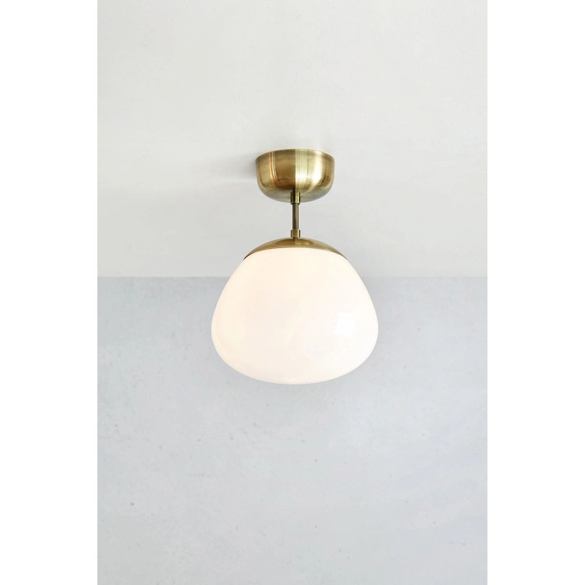 Lampa sufitowa Rise 1xE27 w antycznym mosiądzu z białym, szklanym kloszem w kształcie zaokrąglonego owal. Montowana do sufitu, prezentuje minimalistyczny design, idealna do nowoczesnych wnętrz.