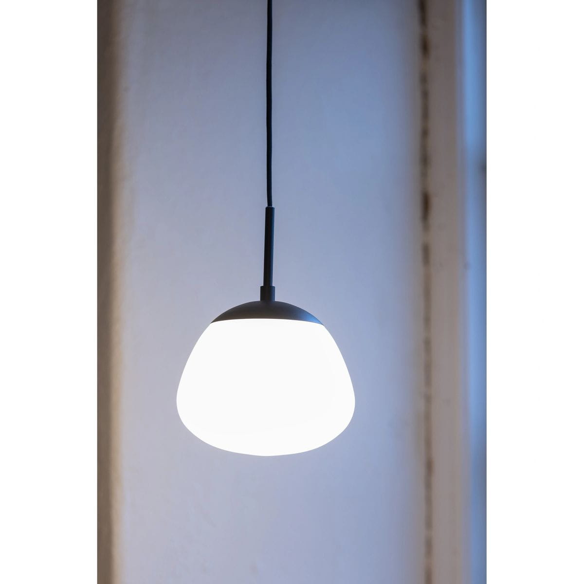 Lampa wisząca Rise D18 w kolorze czarnym i białym, z okrągłym kloszem w kształcie lekko spłaszczonej kuli. Zawieszona na cienkim przewodzie, widoczna w zbliżeniu na neutralnym tle. Przeznaczona na żarówkę E14.