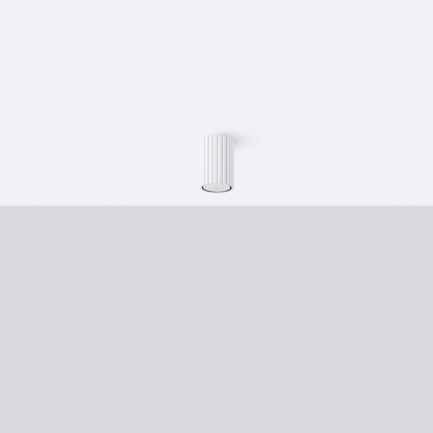 Biała lampa sufitowa Karbon 10 z miejscem na jedną żarówkę GU10, o cylindrycznym kształcie i teksturowanej powierzchni. Zainstalowana na jasnym tle, prezentuje minimalistyczny design.