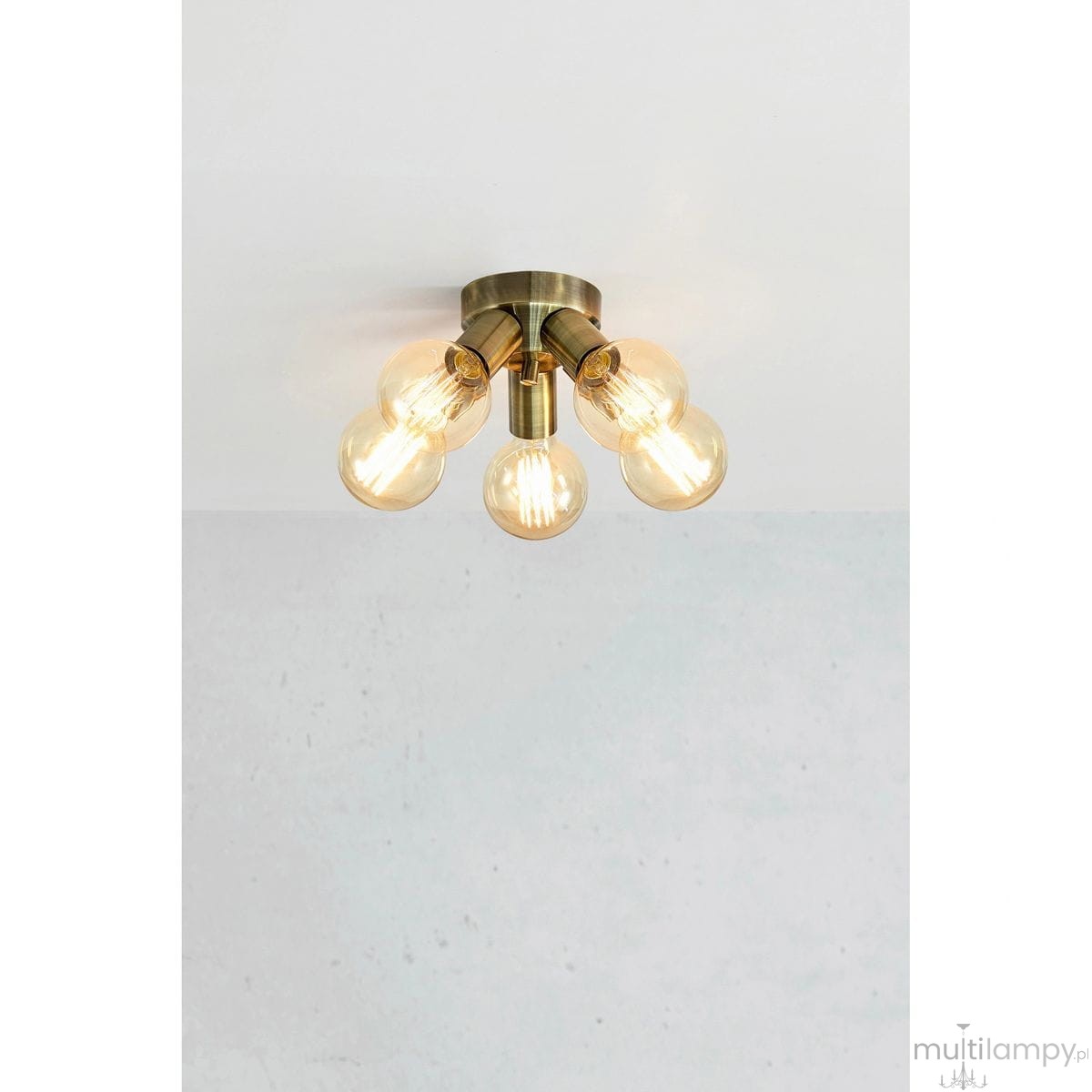 Lampa sufitowa Mazzo w kolorze antycznego mosiądzu, z pięcioma gniazdami E27. Ujęcie z góry, ukazujące okrągłą podstawę i szklane klosze. Gniazda umieszczone są w promieniu, co podkreśla nowoczesny design. Tło jasne, minimalistyczne.