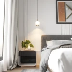 Czarna lampa wisząca Iliso z żarówką LED 10W w formie matowej, okrągłej bańki, zawieszona nad łóżkiem. W tle widoczne nowoczesne meble, roślina w doniczce i dekoracyjny obraz na ścianie.