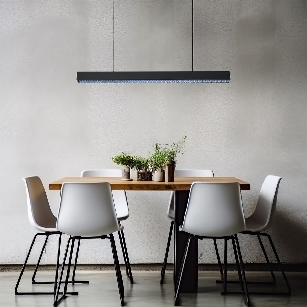 Lampa wisząca Mira 120 w kolorze czarnym, z jednym źródłem światła LED o mocy 45W, zawieszona nad drewnianym stołem z roślinami w doniczkach. Prosty, nowoczesny design, umieszczona w jasnym wnętrzu z białymi krzesłami.