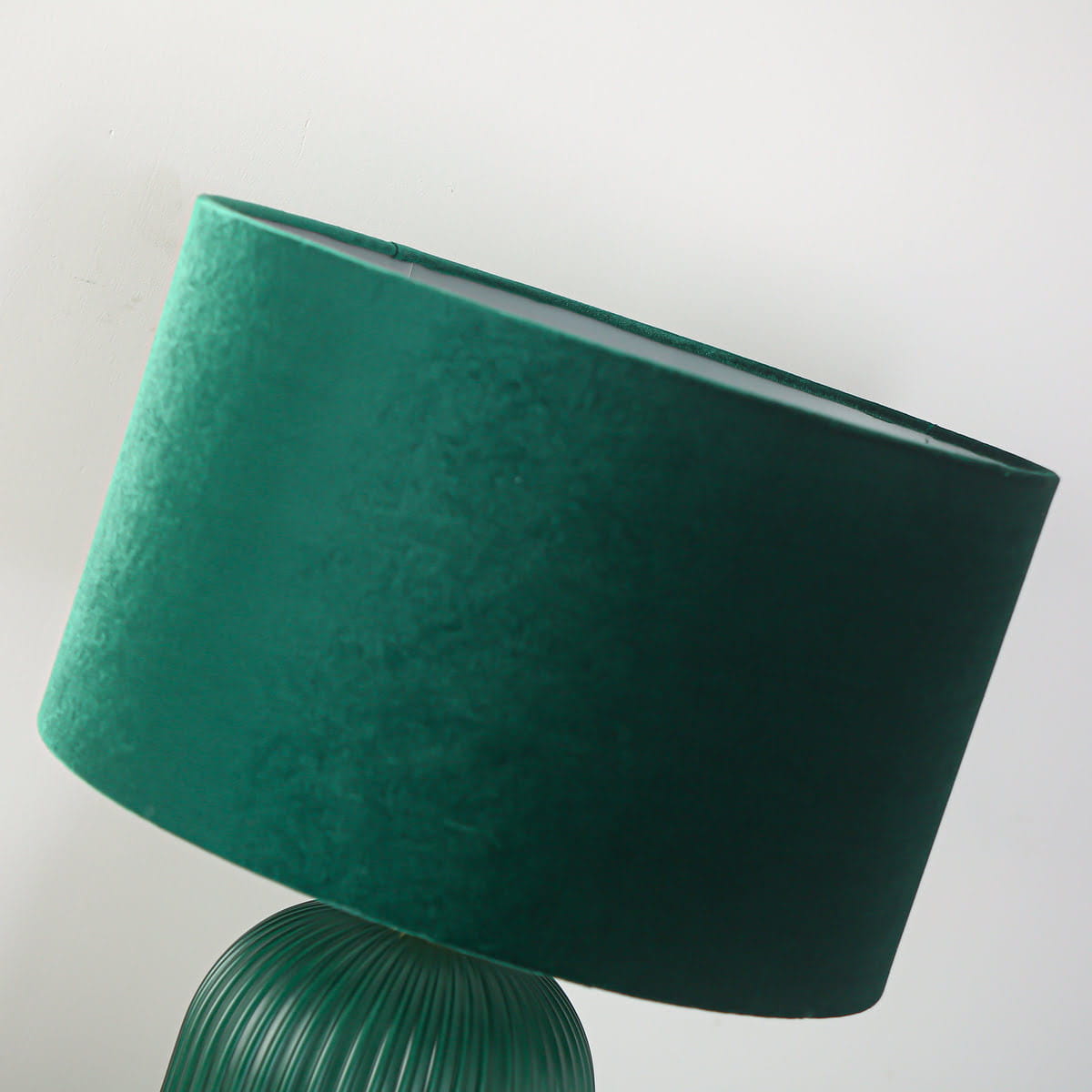 Lampa stołowa Tamiza w butelkowej zieleni, z okrągłym, teksturowanym kloszem z tkaniny. Ujęcie z boku, ukazujące lekko nachyloną górę i żłobioną podstawę. Wysoka, elegancka forma, idealna do stylowego wnętrza.