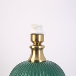 Lampa stołowa Tamiza w butelkowej zieleni, z metalowym, złotym trzonkiem i miejscem na żarówkę E27. Widoczna struktura klosza z pionowymi rowkami. Kąt ujęcia zbliżony na górną część lampy.