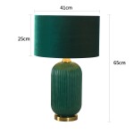 Lampa stołowa Tamiza o wysokości 65 cm, z butelkowo zielonym kloszem i dekoracyjną podstawą. Owalna, żłobiona podstawa w odcieniu zieleni. Klosz ma średnicę 41 cm i wysokość 25 cm, całość na złotym elemencie mocującym.