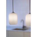 Lampa wisząca Cava w kolorze czarnym i białym z trzema kloszami E14. Klosze o zaokrąglonym kształcie z fakturą pionowych rowków, zawieszone na czarnych przewodach. Widoczna kuchnia w tle z zlewem.