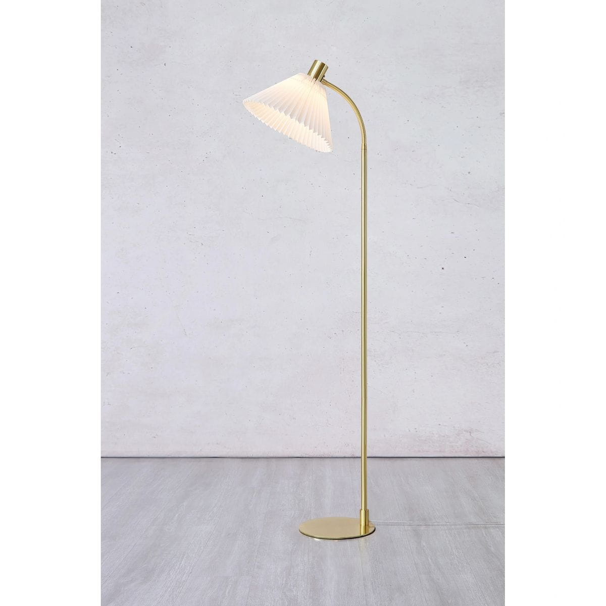 Lampa podłogowa Mira z podstawą w kolorze szczotkowanego mosiądzu i kloszem w białym kolorze, o eleganckim, zaokrąglonym kształcie. Ujęcie frontalne, stojąca, minimalistyczny design, na jednolitym tle.