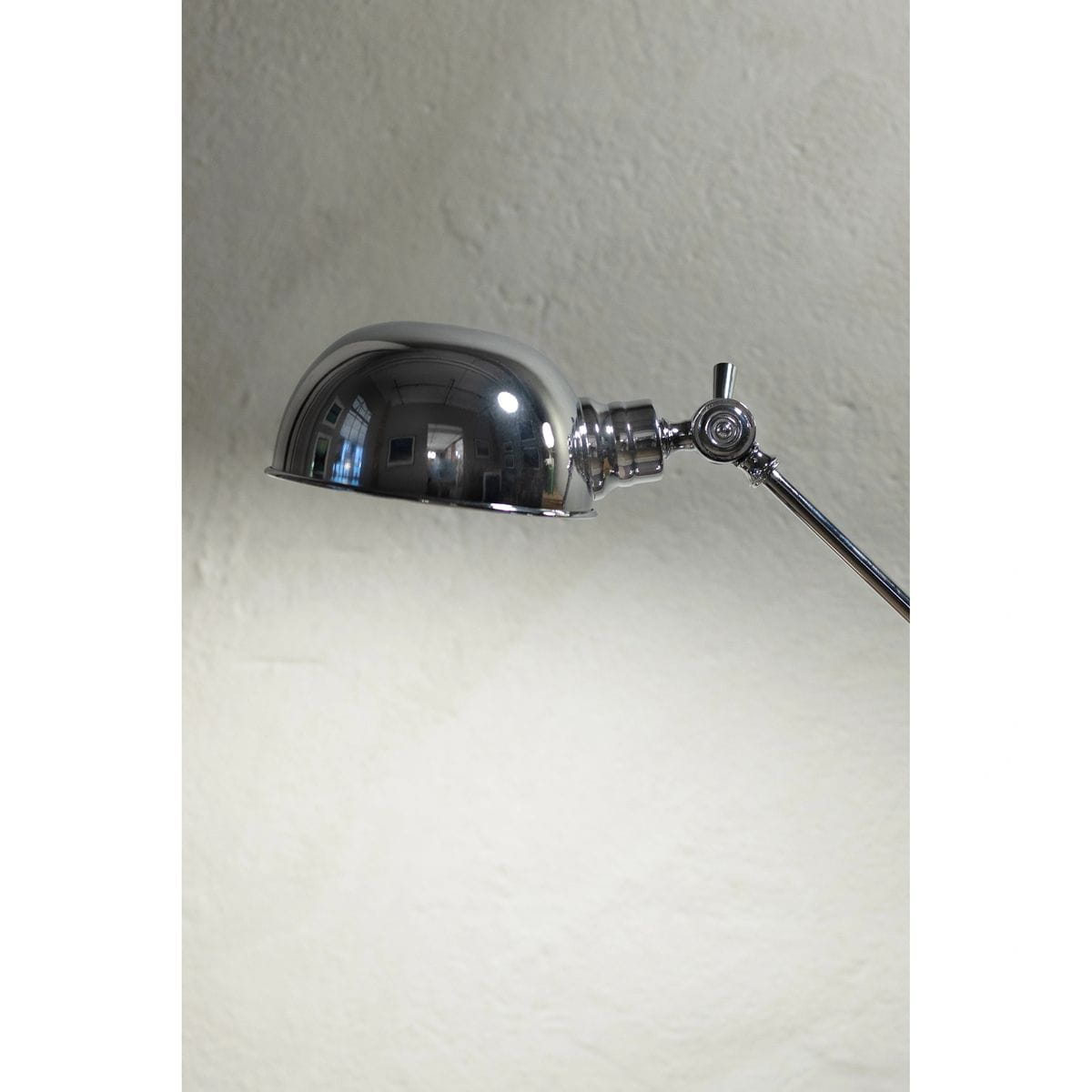 Lampa biurkowa Portland z chromowanym kloszem w kształcie półkuli i regulowanym ramieniem. Ujęcie z boku, ukazujące detale mocowania i błyszczący materiał. Idealna do biura lub domowego wnętrza.