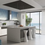 Biała lampa wisząca Karbon 1 z jednym źródłem światła GU10, zawieszona nad nowoczesnym blatem kuchennym. W tle widoczne duże okno z widokiem na morze oraz minimalistyczne, białe stołki. Oświetlenie dodaje elegancji wnętrzu.