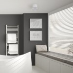 Biała lampa sufitowa Kendal LED IP54, okrągła, zamontowana w suficie, w nowoczesnym wnętrzu z szarymi ścianami, obok białych ramek ze zdjęciami oraz półką z ręcznikami. Lampa jest w pozycji wiszącej, zapewniając oświetlenie.