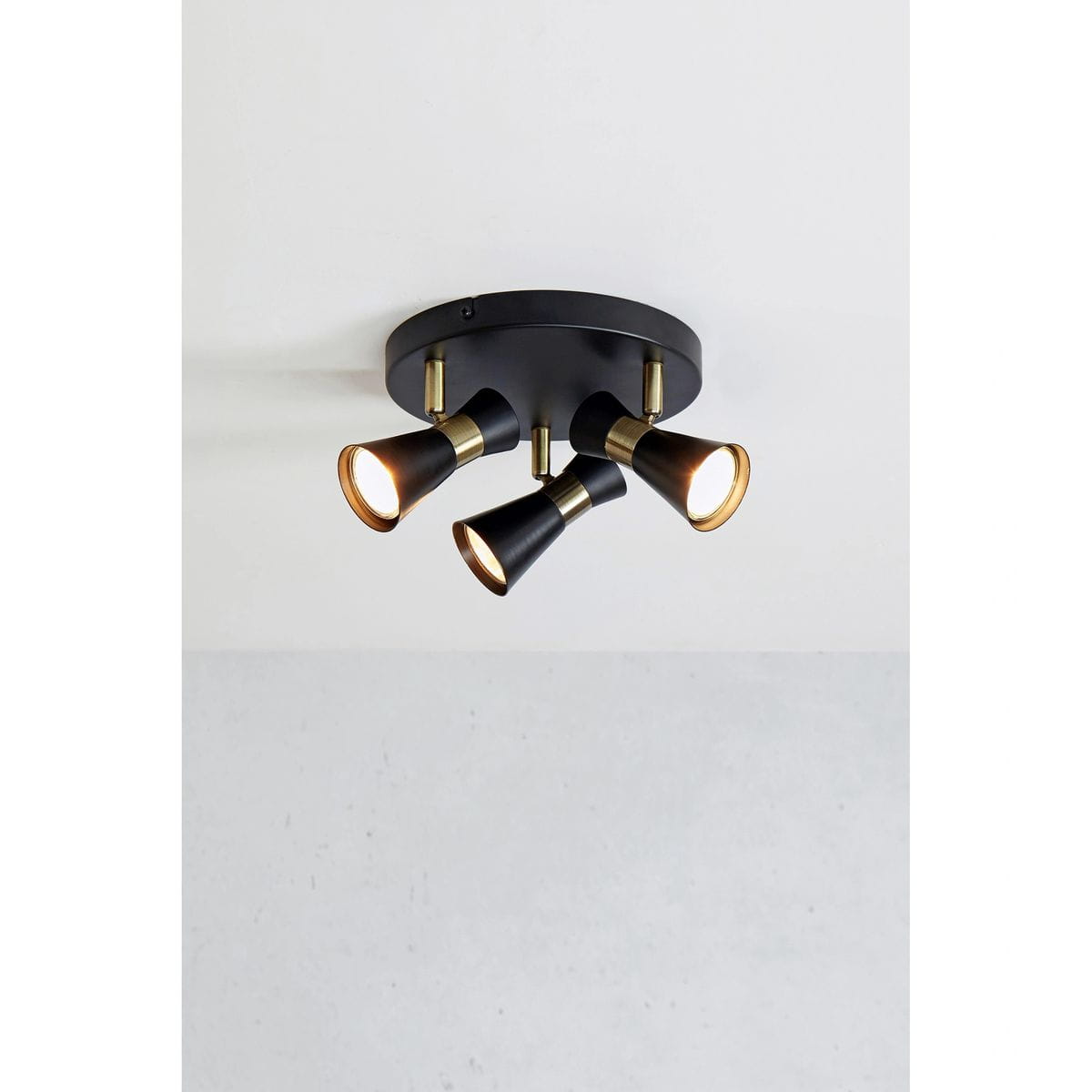 Lampa sufitowa (spot) z trzema źródłami światła GU10, w kolorze czarnym z elementami antycznego mosiądzu. Produkt zamontowany na okrągłej podstawie, z reflektorami skierowanymi w różne strony, idealny do nowoczesnych wnętrz.
