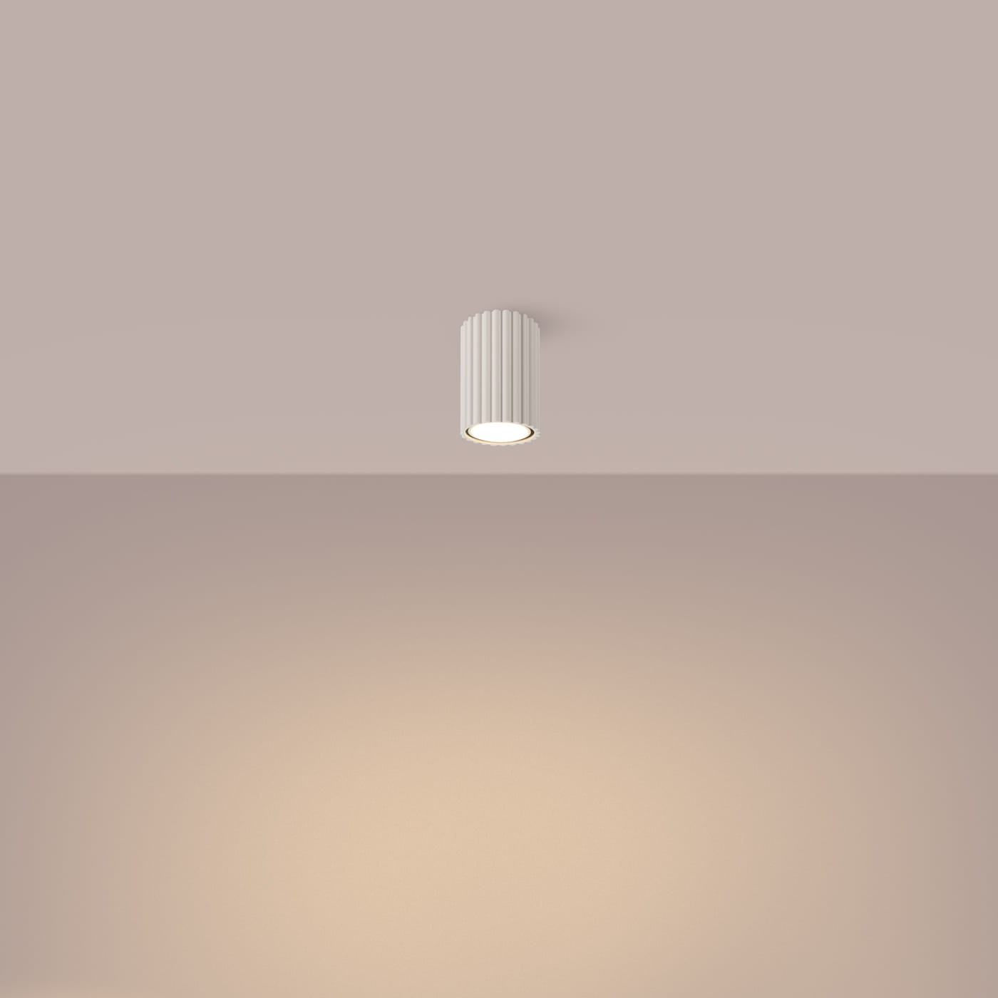 Beżowa lampa sufitowa Karbon 10 z jednym źródłem światła GU10, o cylindrycznym kształcie z rowkowaną teksturą. Umieszczona na suficie, zapewnia delikatne oświetlenie w pomieszczeniu o jasnym tle.