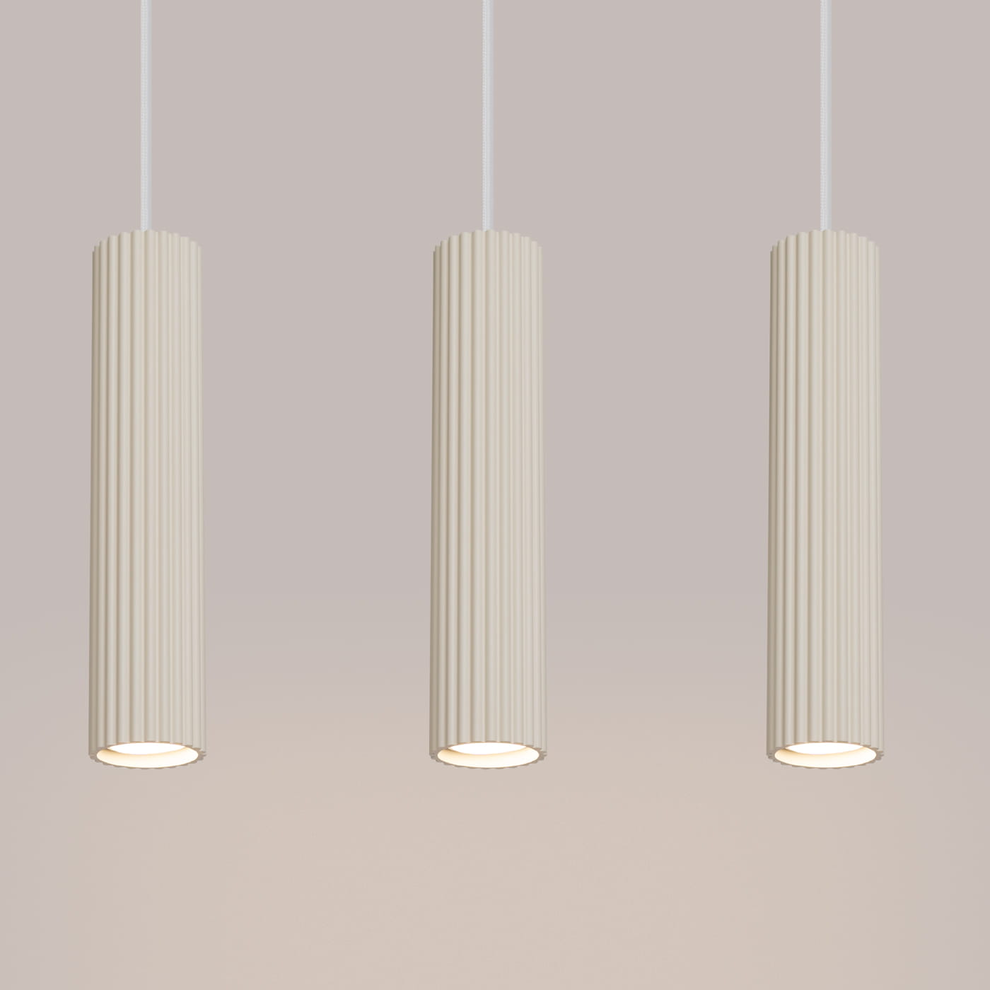 Lampa wisząca Karbon 3 w kolorze beżowym, składająca się z trzech cylindrycznych kloszy z teksturowaną powierzchnią. Ujęcie frontalne, wisząca na białych przewodach, z widocznymi oprawkami na żarówki GU10.