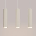 Lampa wisząca Karbon 3 w kolorze beżowym, składająca się z trzech cylindrycznych kloszy z teksturowaną powierzchnią. Ujęcie frontalne, wisząca na białych przewodach, z widocznymi oprawkami na żarówki GU10.