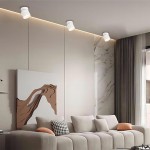 Biała lampa sufitowa Kendal (spot) 1xGX53, zamontowana na suficie, z ruchomym kloszem, o minimalistycznym designie. W tle jasne ściany i nowoczesny obraz, otoczenie w strefie wypoczynkowej.