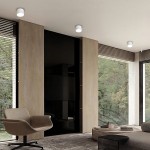 Biała lampa sufitowa Kendal z oprawą GX53, zamontowana na suficie w nowoczesnym wnętrzu. Kształt cylindryczny, minimalistyczny design. Widoczna w kontekście pokoju z drewnianymi panelami i dużymi oknami z roletami.