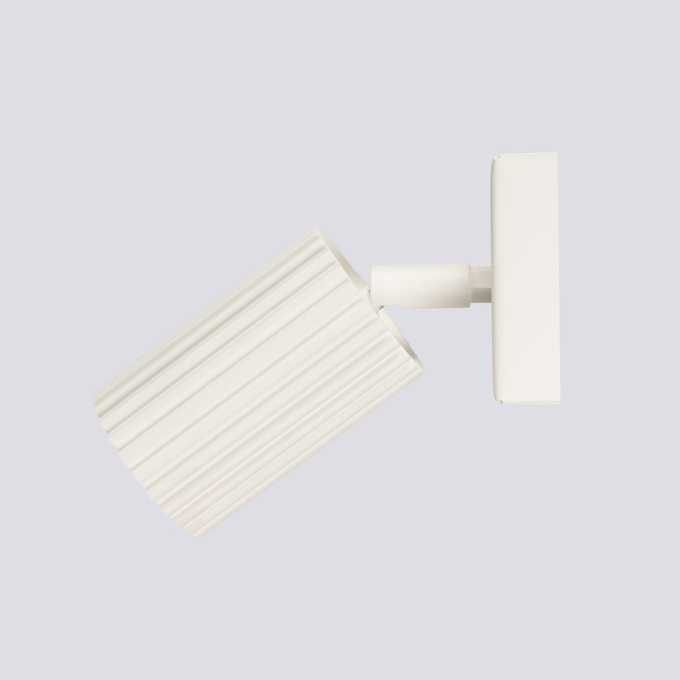 Beżowy kinkiet Karbon 1xGU10 z okrągłym kloszem o fakturze żłobkowanej, zamontowany na prostokątnej podstawie. Ujęcie z boku, klosz skierowany lekko w dół, na jednolitym tle. Idealny do oświetlenia wnętrz.