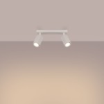 Beżowa lampa sufitowa typu spot z dwoma oprawami GU10, umieszczona na prostokątnej podstawie. Reflektory o fakturze żłobionej, skierowane w różnych kierunkach, montowane na suficie. Tło w delikatnym odcieniu beżu.